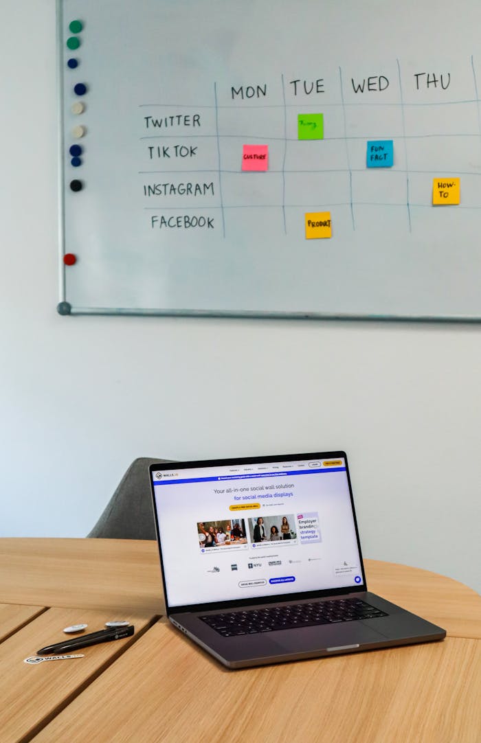 mission-img A modern office setup featuring a laptop and a whiteboard schedule for social media platforms.